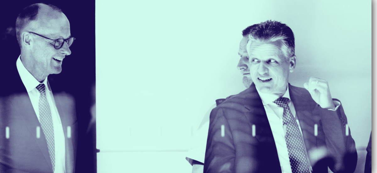 Friedrich Merz (links) und Thorsten Frei (rechts) in Anzug und Krawatte während eines Gesprächs. Das Foto ist durch eine Glasscheibe aufgenommen und in einem blaugrünen Farbton gestaltet.