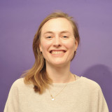 Das Bild zeigt die Kandidatin Johanna Isensee vor einem lilafarbenen Hintergrund