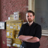 Tim Wetzel, in schwarzer Kleidung, vor einer roten Wand