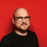 Christoph Nießen Portraitaufnahme von Christoph Nießen vor rotem Hintergrund