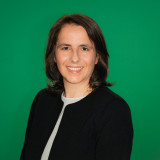Doreen Frowitter grüner Hintergrund, Profilbild bis Brusthöhe, schwarzes Jackett