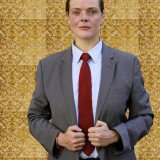 Almut Buchwald Buchwald in grauem Anzug, blauem Hemd, roter Krawatte vor goldener Tapete (Foto: A.Rost)
