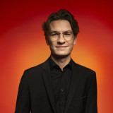 Vincent Kilian vor einem farbigen Hintergrund