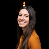 Agnes im orangenen Oberteil mit schwarzem Hintergrund