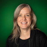 Anne Kathrin Warnecke Portraitfoto Kathrin Warnecke vor dunkelgrünem Hintergrund