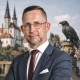 Daniel Wald Daniel Wald im dunkelblauen Anzug mit weißem Hemd und bordeauxfarbener Krawatte. Im Hintergrund sind der Merseburger Dom und Schloss, sowie eine Rabenstatue aus der Rabensage, mit dem Ring zu sehen.