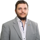 Leon Suchanek Bild Leon Suchanek, ein weißes Hemd mit zwei offenen Knöpfen und einem grauem Sakko.