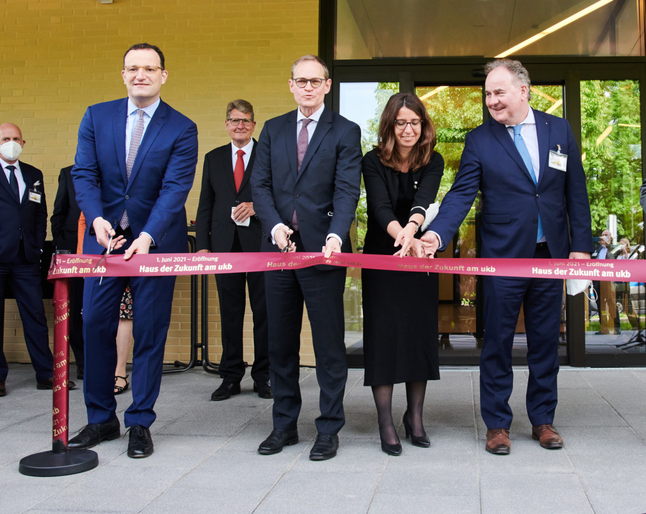 Jens Spahn, Michael Müller, Nadja Zivkovic und Horst Riesenberg-Modeja stehen vor dem Haus der Zukunft und schneiden ein rotes Band durch.